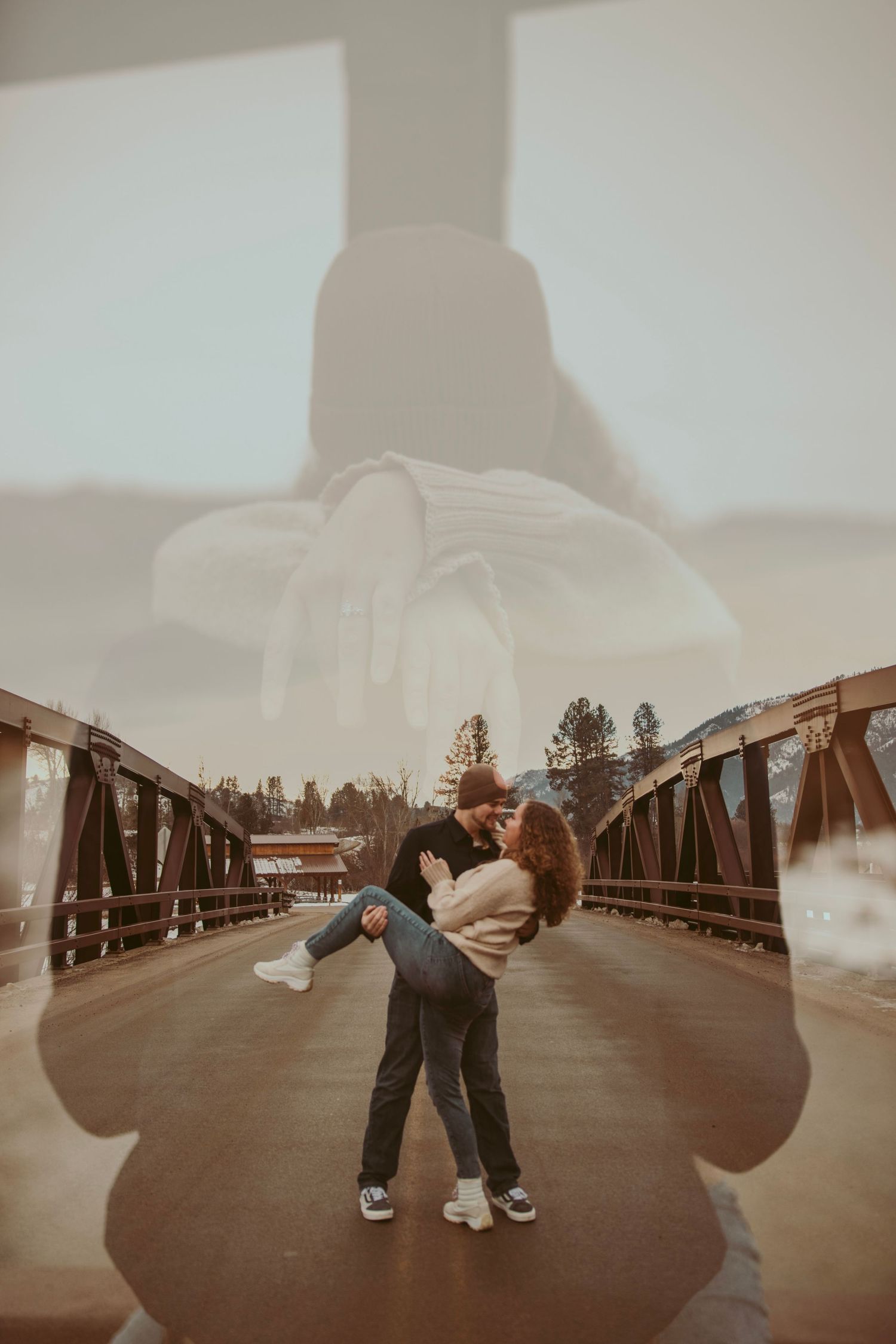 Silhouettes dancing on a bridge at sunset with mountains in the background.