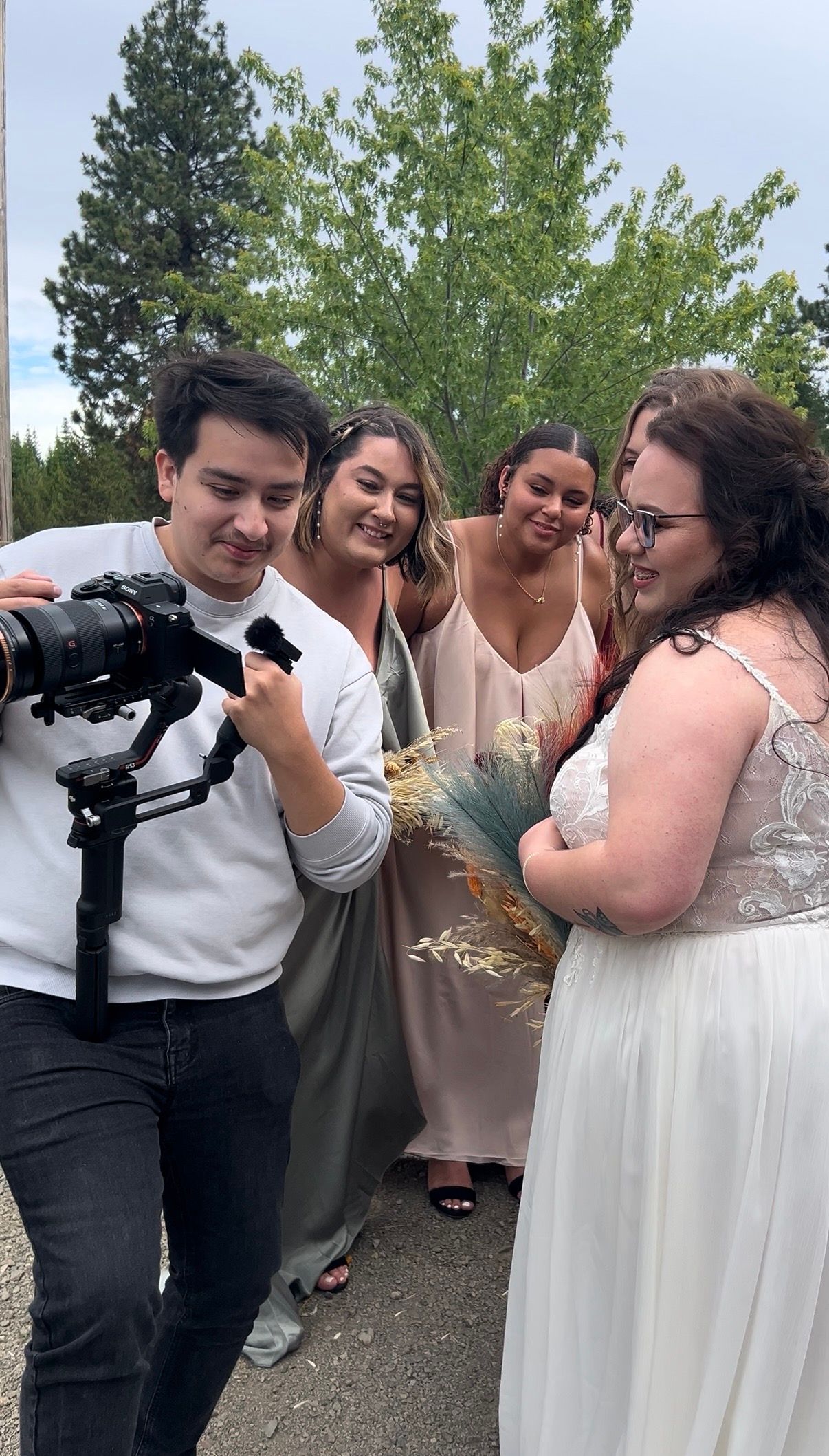 Wedding party members take photos of each other with cameras in an outdoor setting.