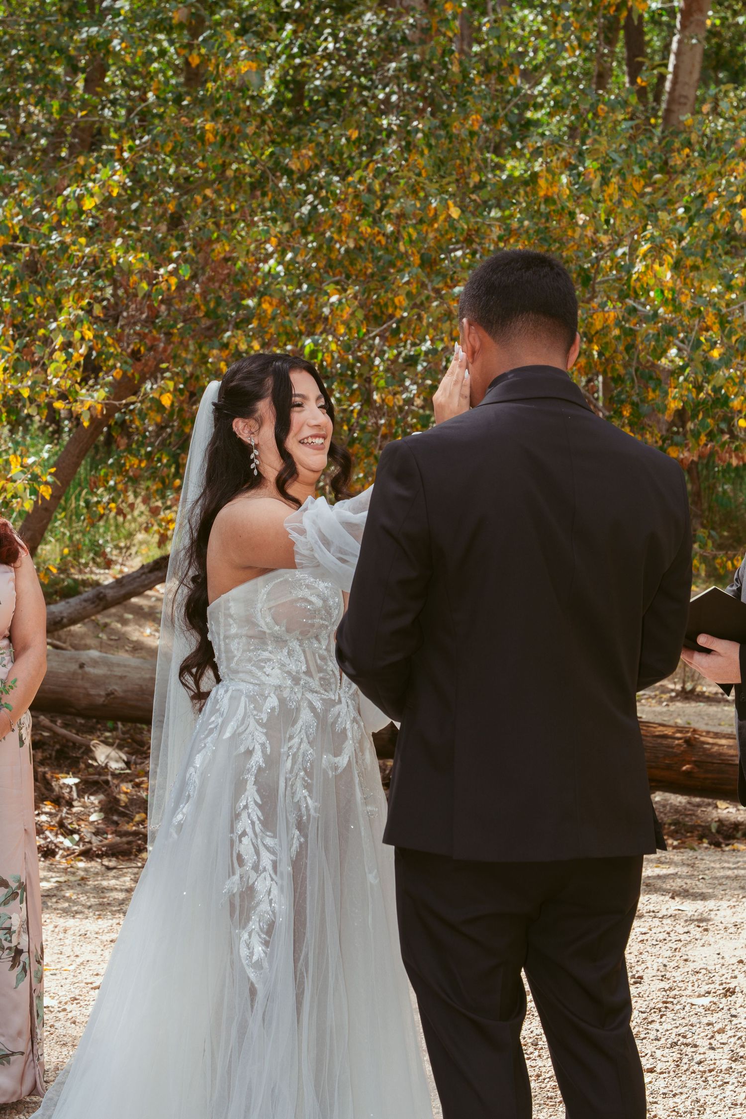A couple participates in their wedding ceremony among fall foliage and natural surroundings.