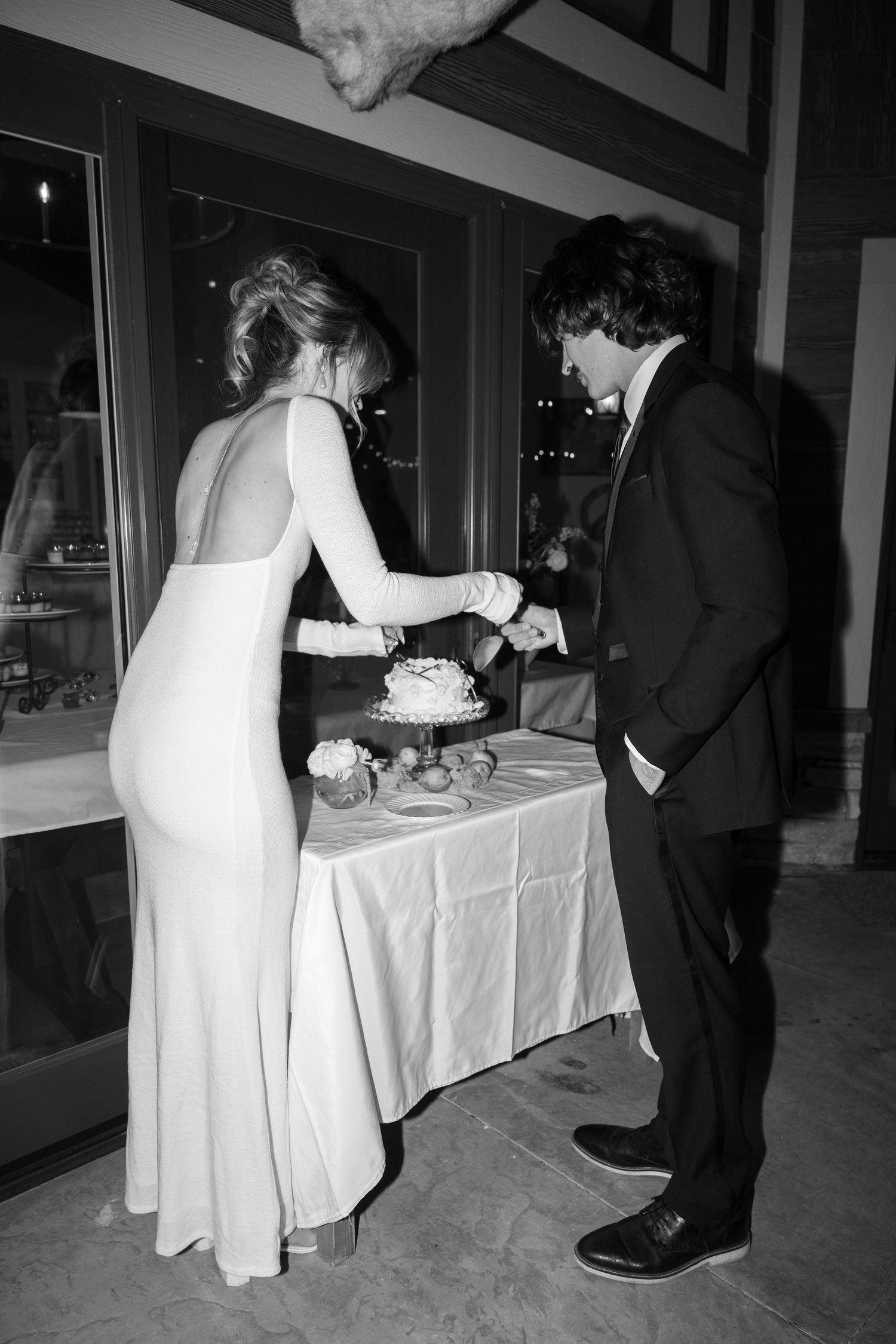 Black and white photo of newlyweds sharing cake at their wedding reception.