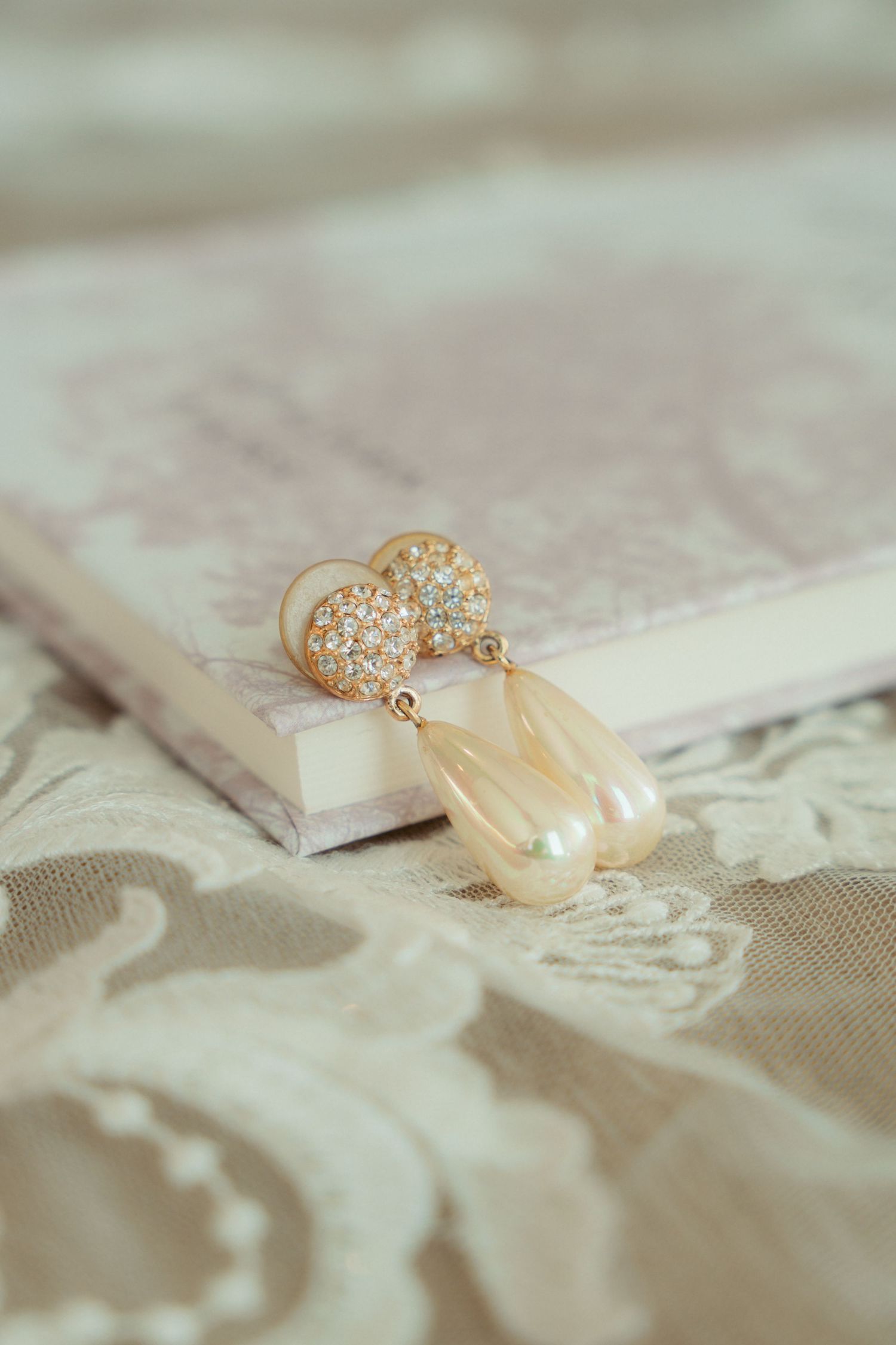 Delicate pearl and crystal bridal jewelry on lace fabric.