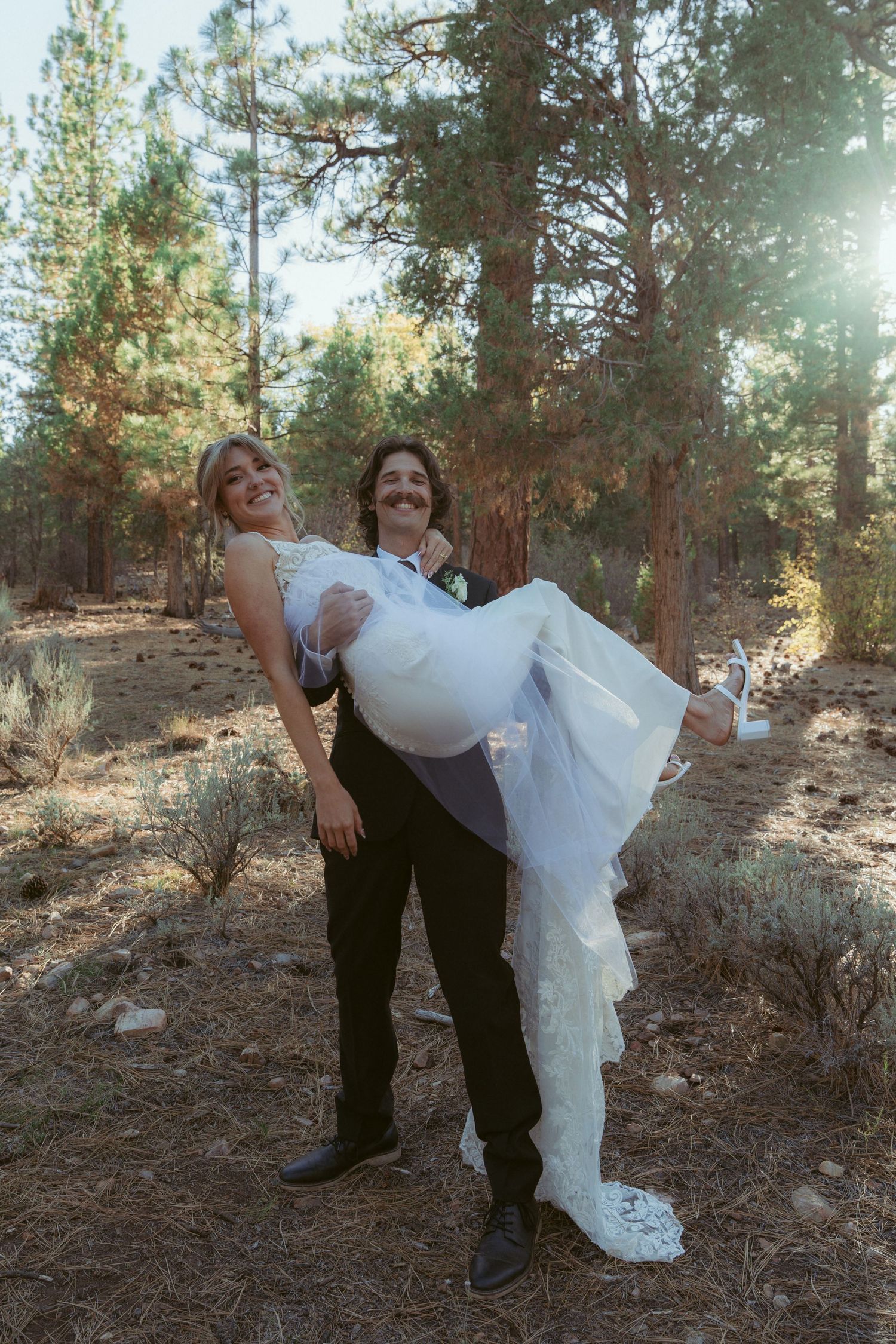 Playful wedding photos showing the couple in a dip pose among tall pine trees.