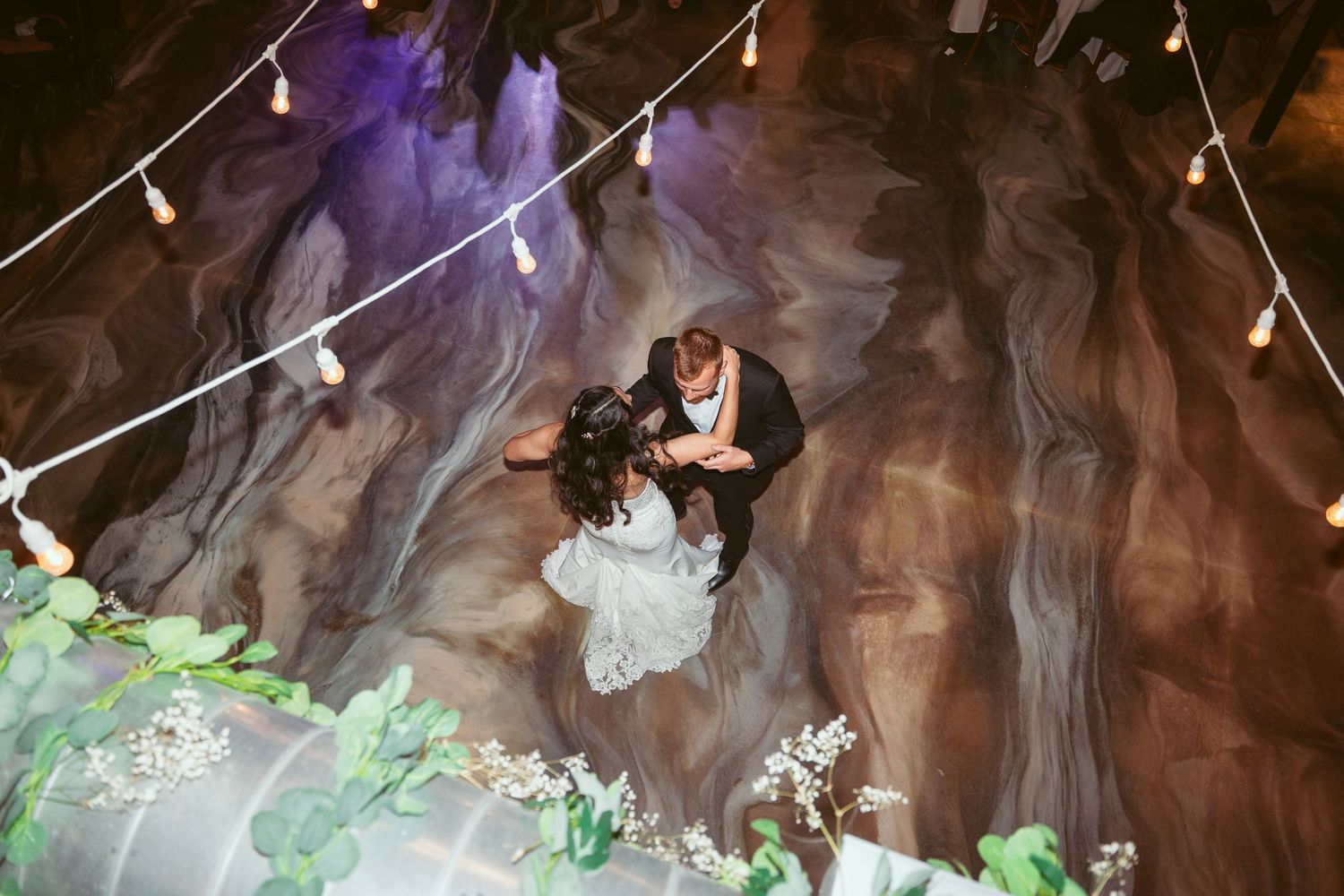 Wedding dance floor illuminated by warm string lights creates romantic atmosphere.