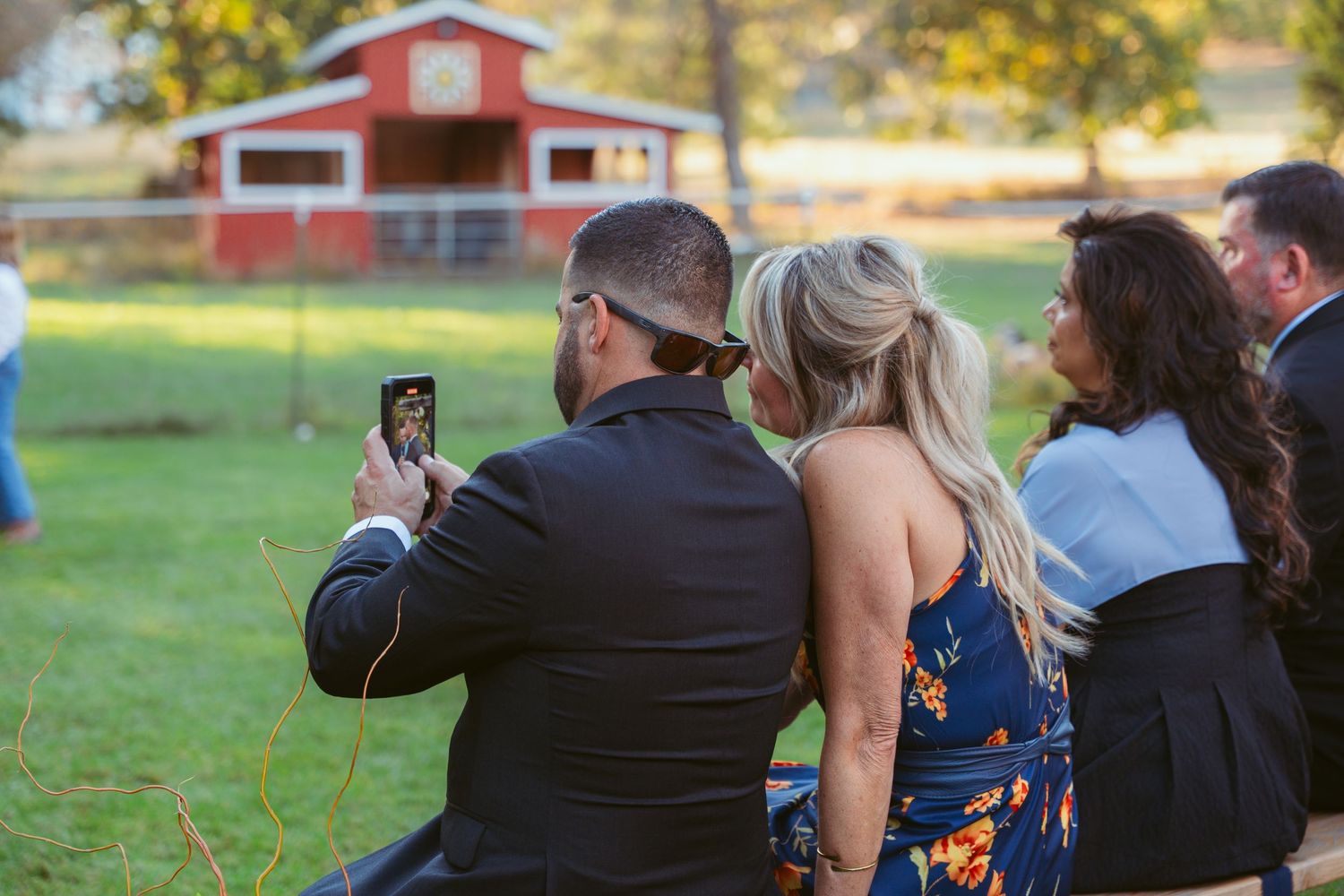 Wedding party laughing together during outdoor autumn ceremony with golden foliage in background.