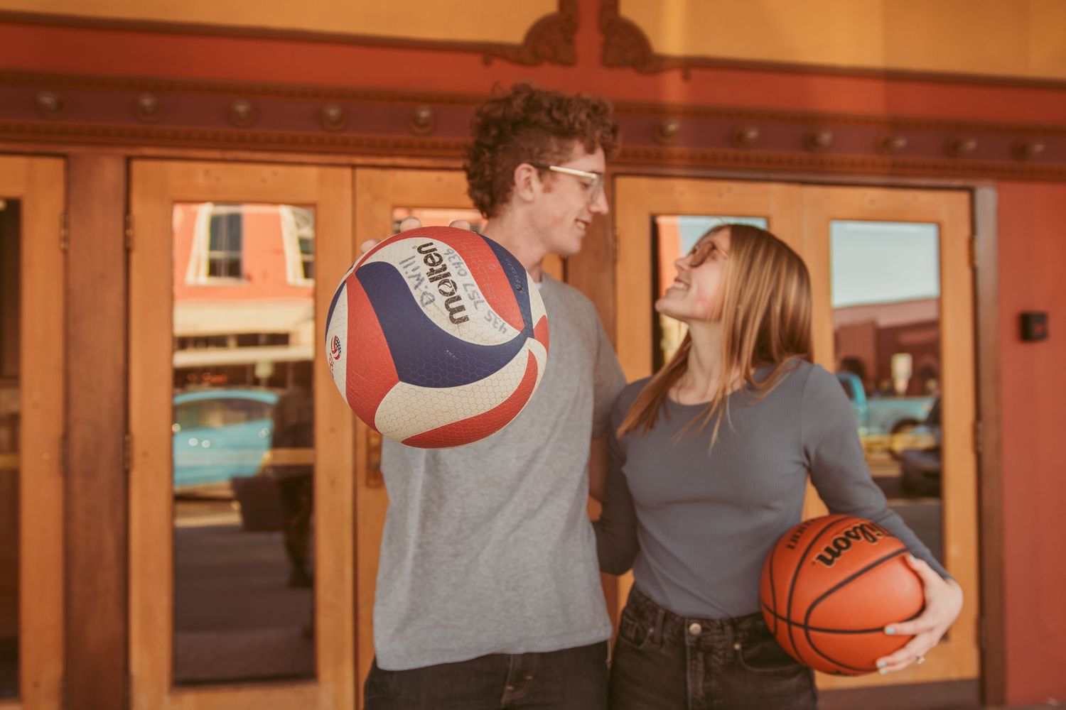 Couple posing with a basketball in a rustic indoor setting.