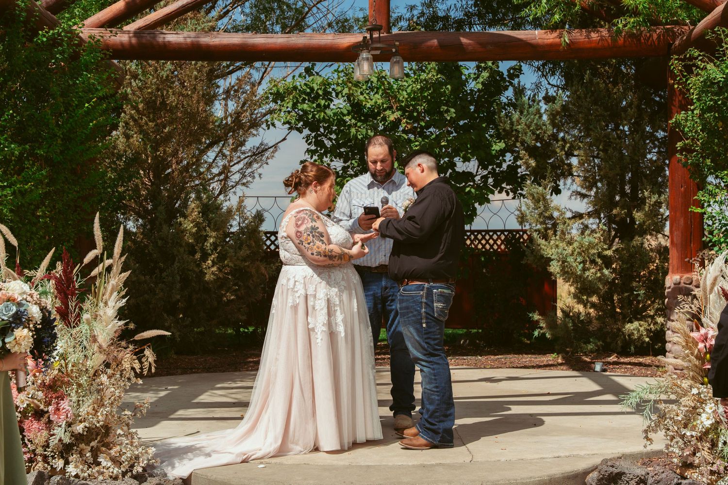 Outdoor wedding ceremony setup with floral decorations and wooden beams creating an archway.