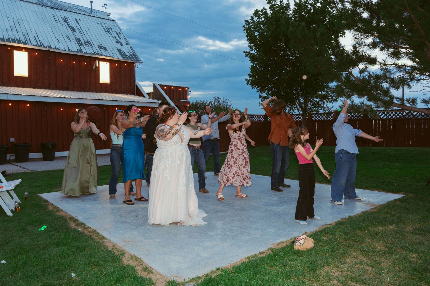Wedding guests dancing and celebrating on an outdoor patio during daytime festivities.