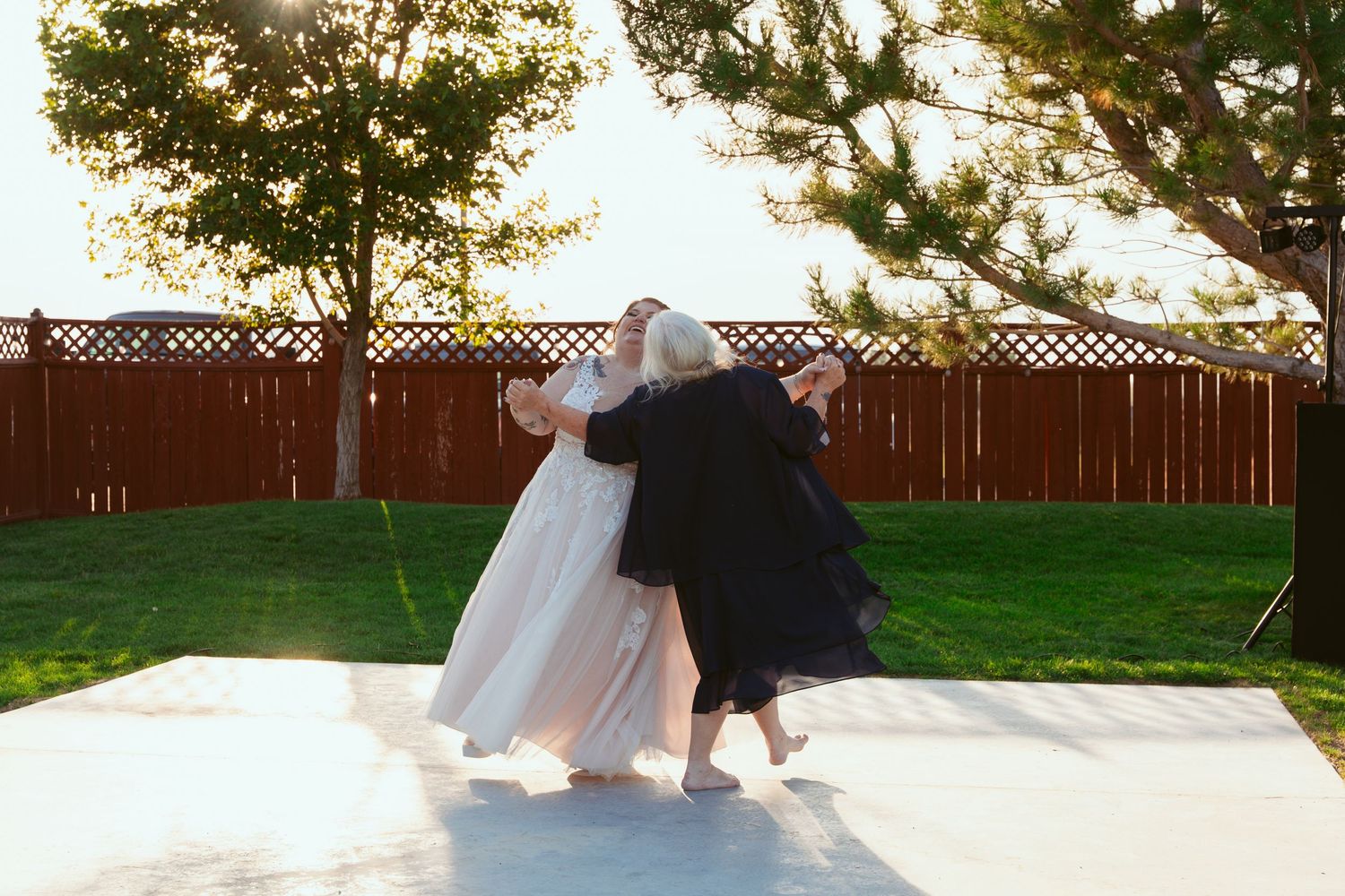 A couple performs a romantic dance dip on an outdoor white dance floor at sunset.