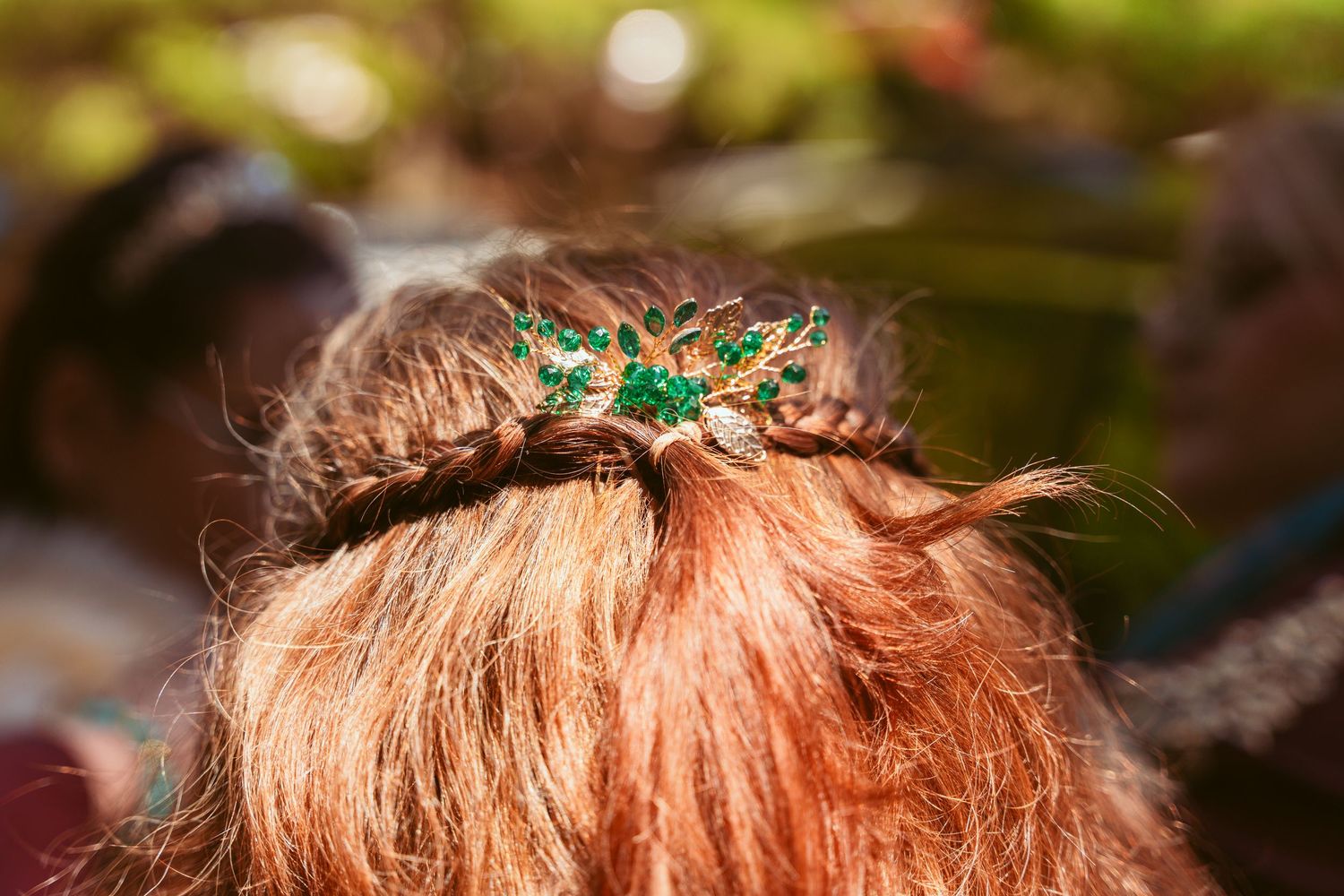 Close-up of an emerald green hair accessory against red hair in natural lighting.