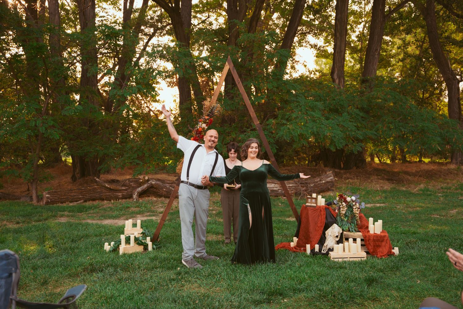 A celebratory moment between newlyweds under a wooden arch with decorative candles.