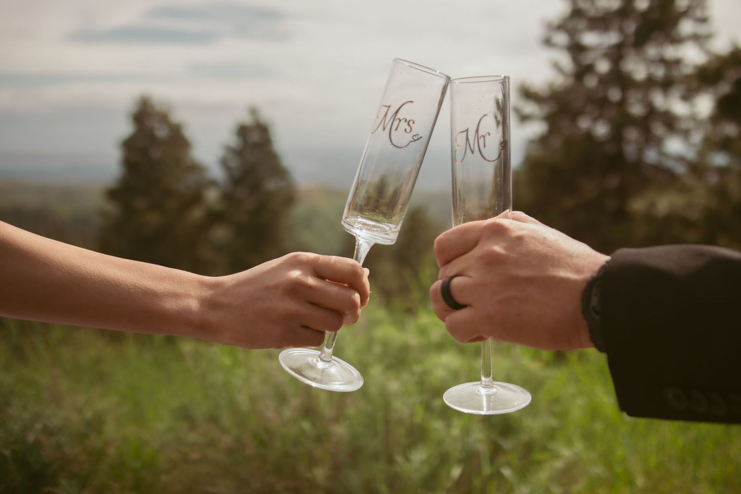 Champagne glasses clink together during a romantic mountain wedding ceremony.