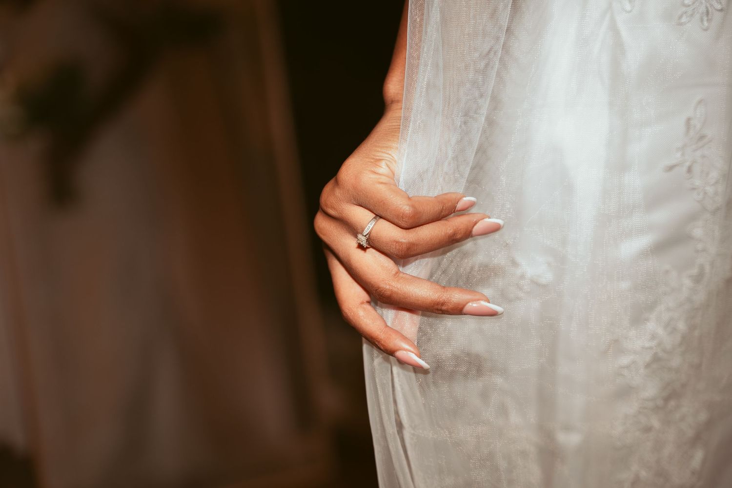 Close-up details of an elegant white lace wedding dress with delicate beading and embellishments.