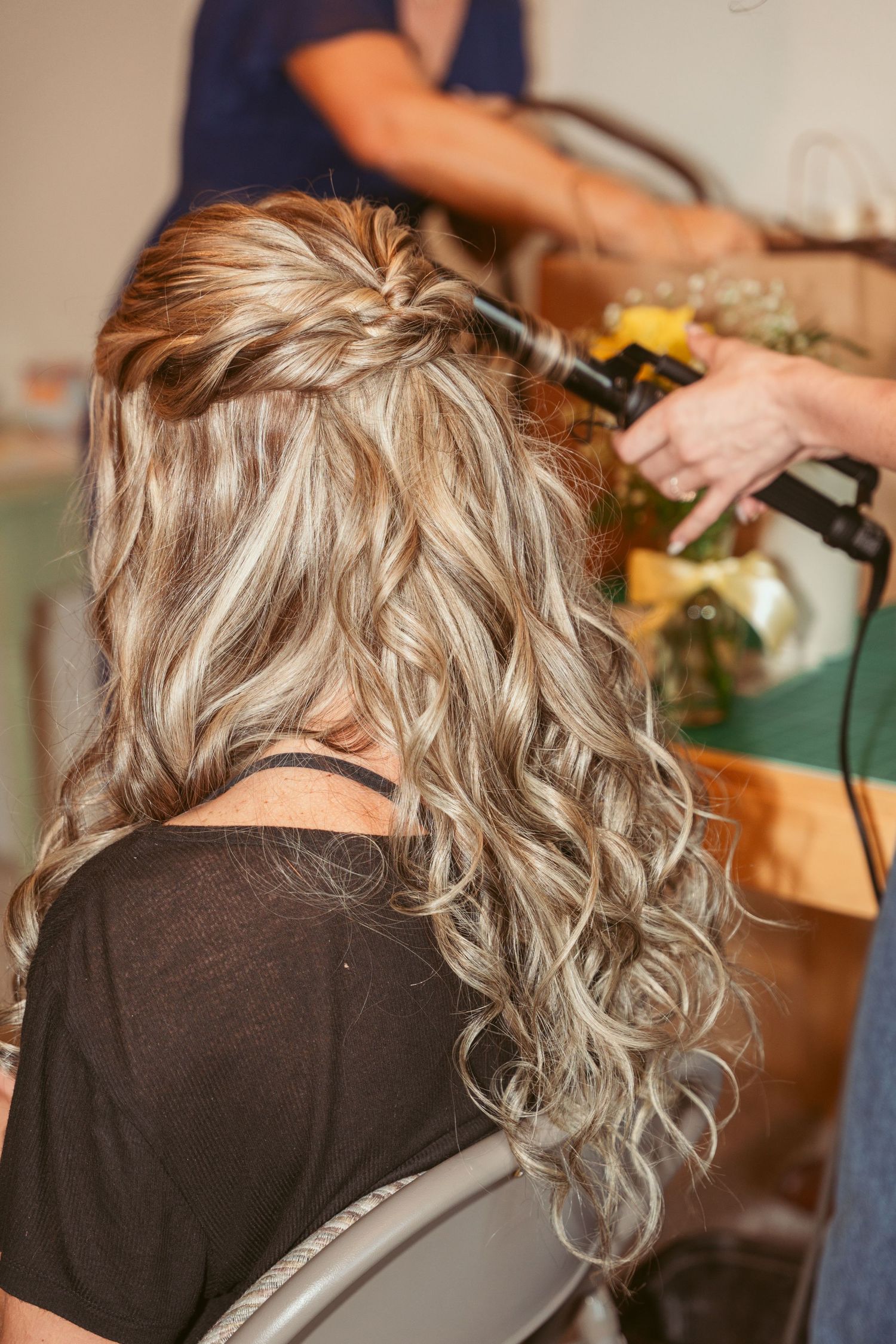 Close-up of blonde curly hair being styled with hair tools.