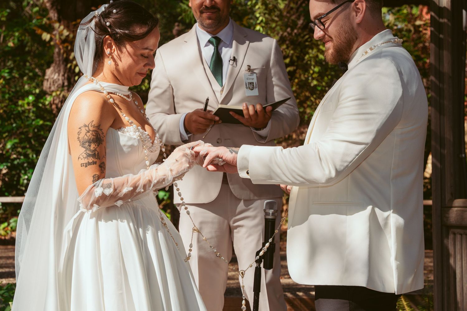 Wedding party in light colored formal attire dancing together in a garden setting during a celebration.