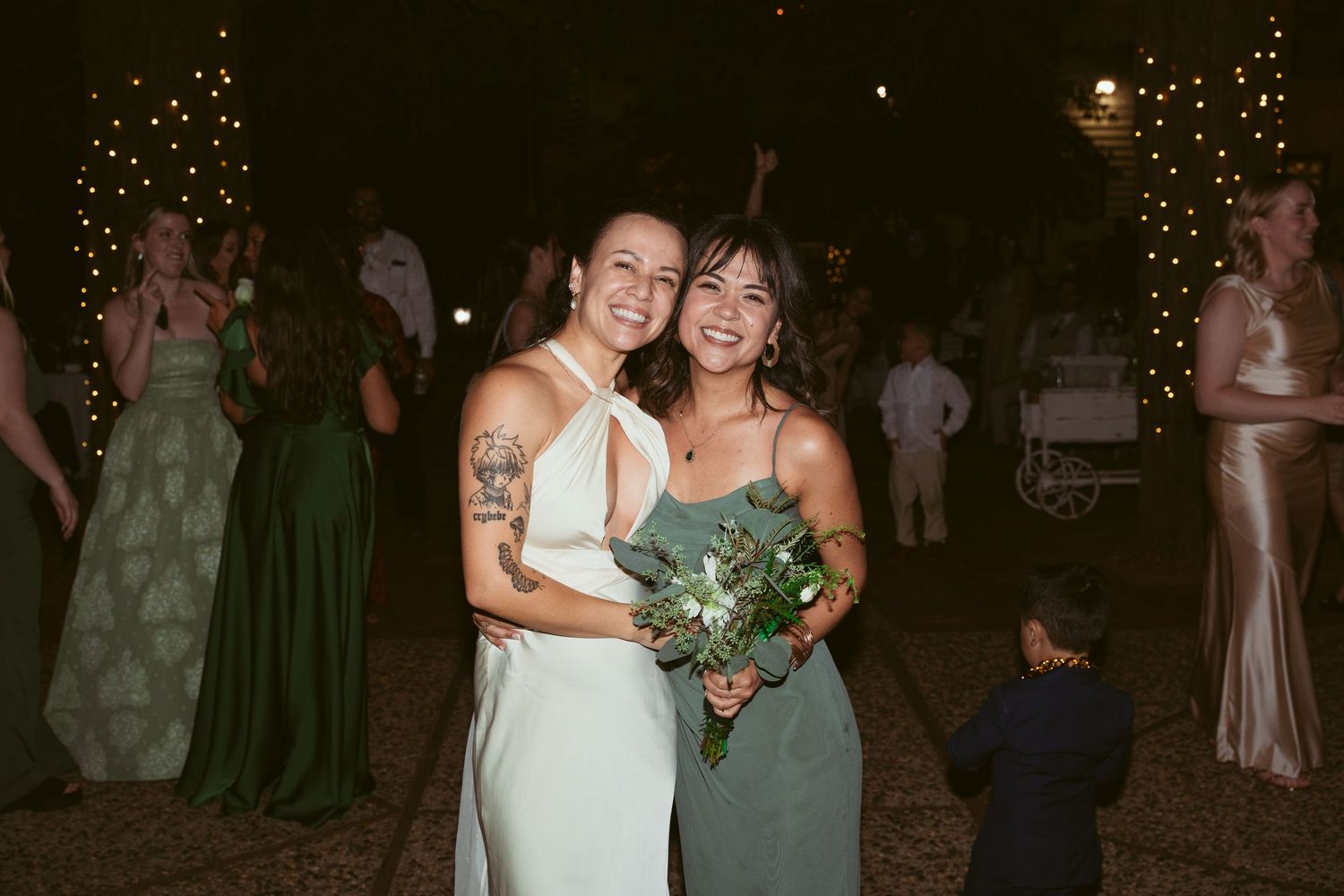 Nighttime wedding celebration with string lights illuminating dancing guests.