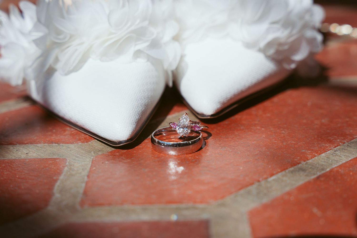 Close-up sequence showing a wedding ring being placed on a finger against a red background.