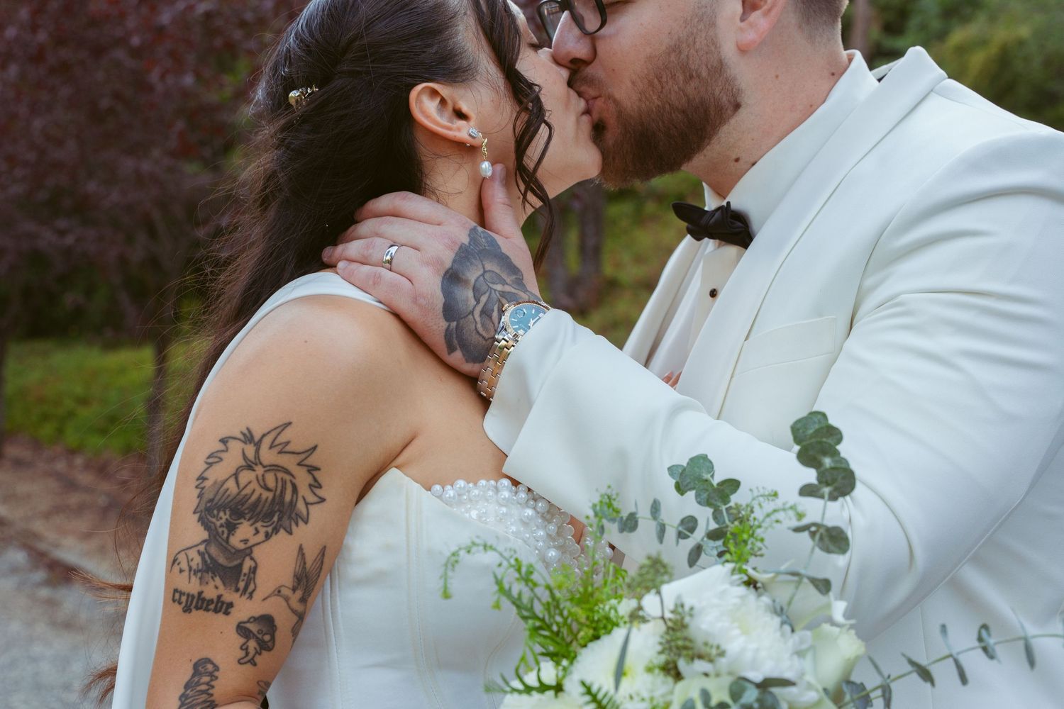 Tender wedding moment captured with white bouquet and formal attire against natural backdrop.