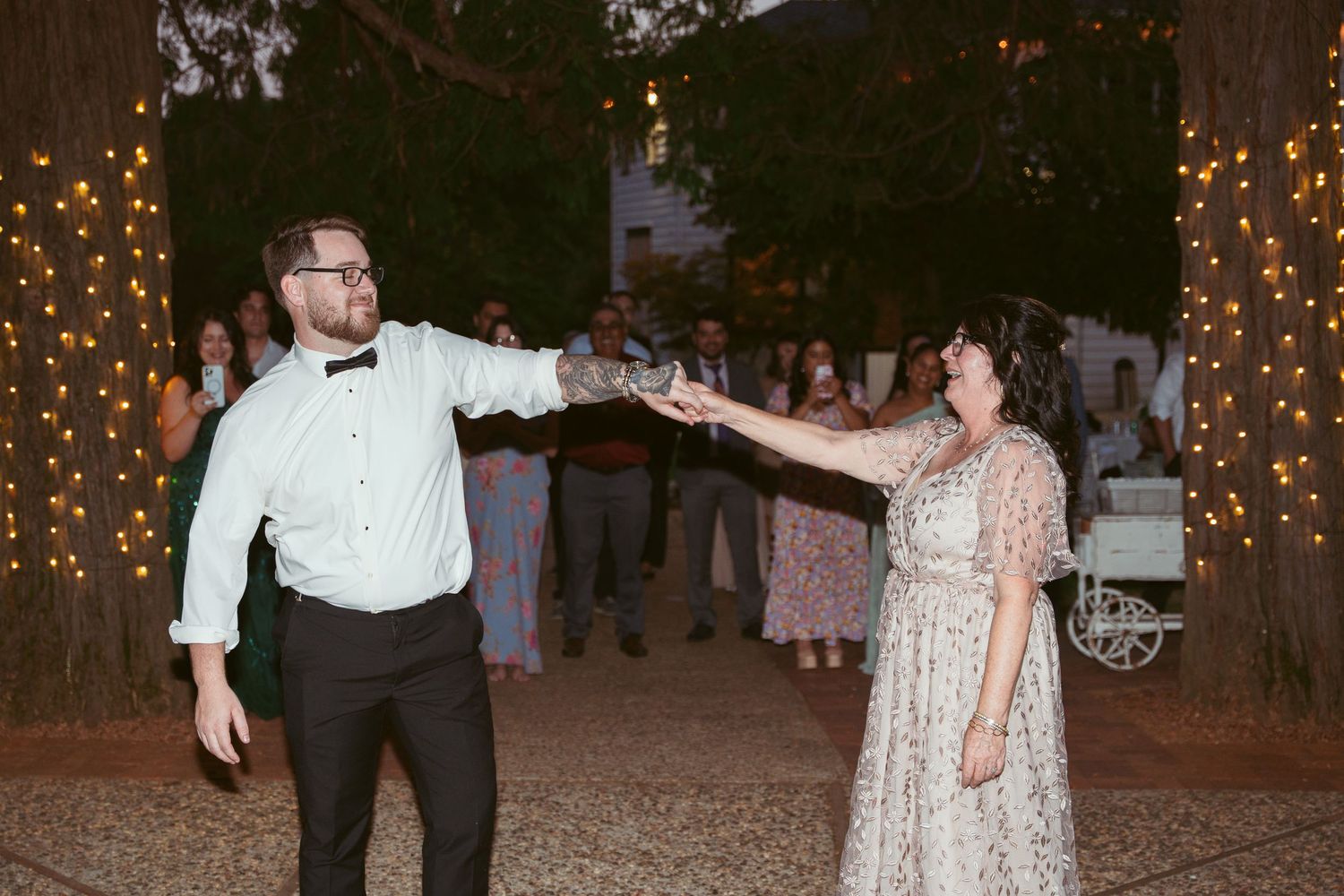 Couple performs choreographed dance move at outdoor evening reception.