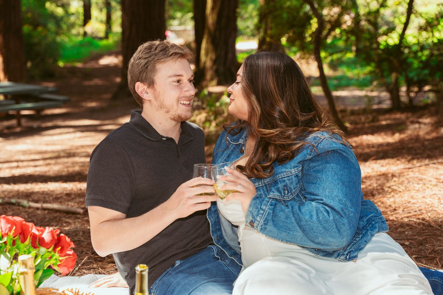 A cozy forest picnic scene with wine bottles and fresh baguettes in a rustic basket.