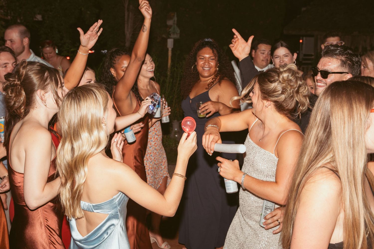 Guests in formal attire dancing and celebrating at a nighttime outdoor party.