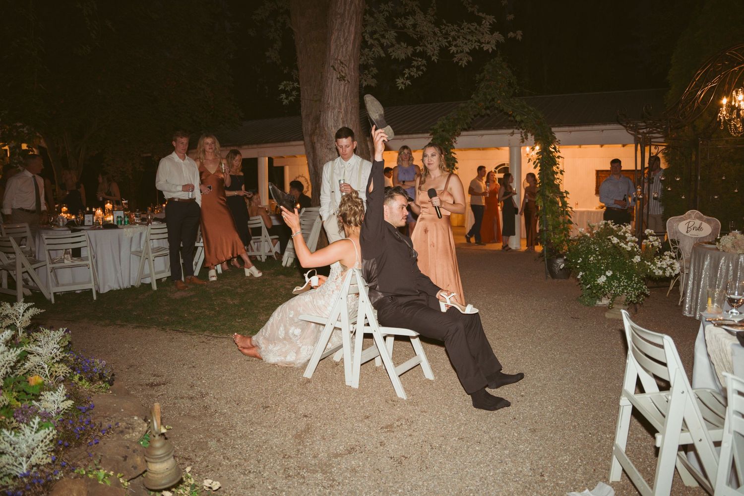 Guests gather around during a traditional chair-lifting celebration at an outdoor wedding reception.