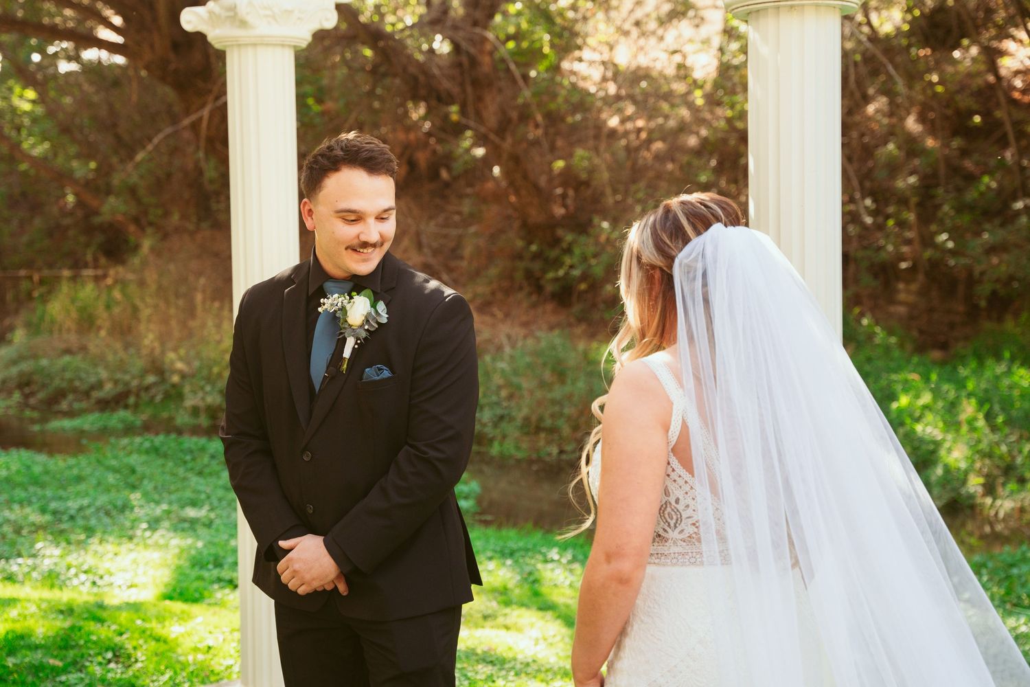 A couple shares an intimate moment during their wedding first look in a garden setting at sunset.