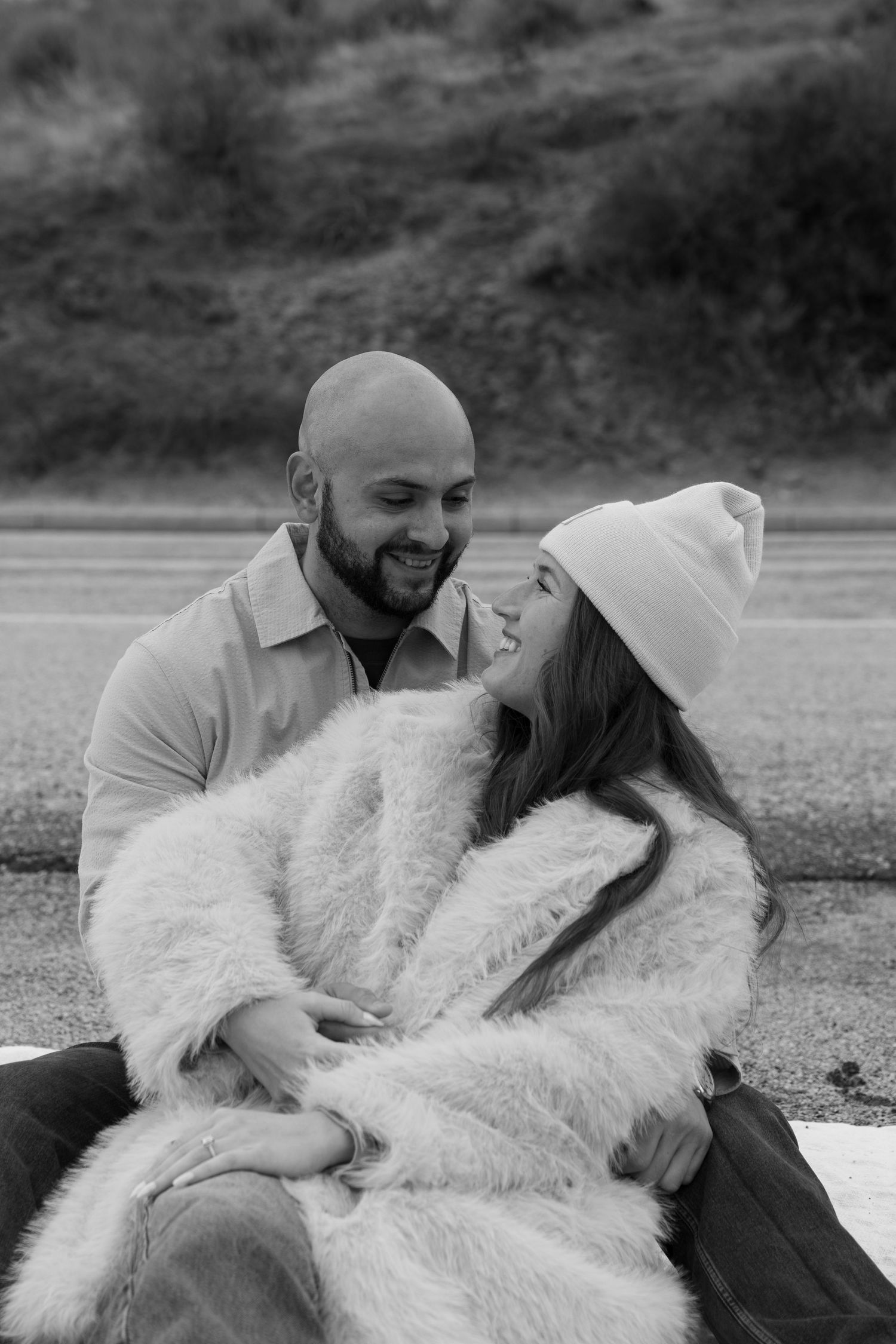 Romantic black and white photo showing affection on a blanket outdoors.