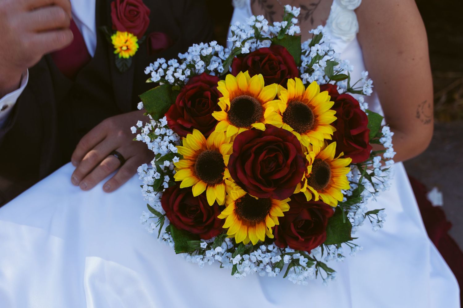 Close-up details of wedding bouquet featuring sunflowers and deep red roses.
