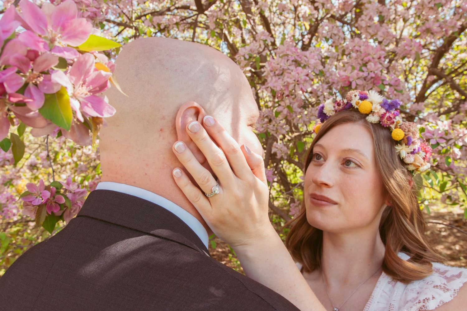 Cherry blossoms frame a romantic moment under pink spring blooms.