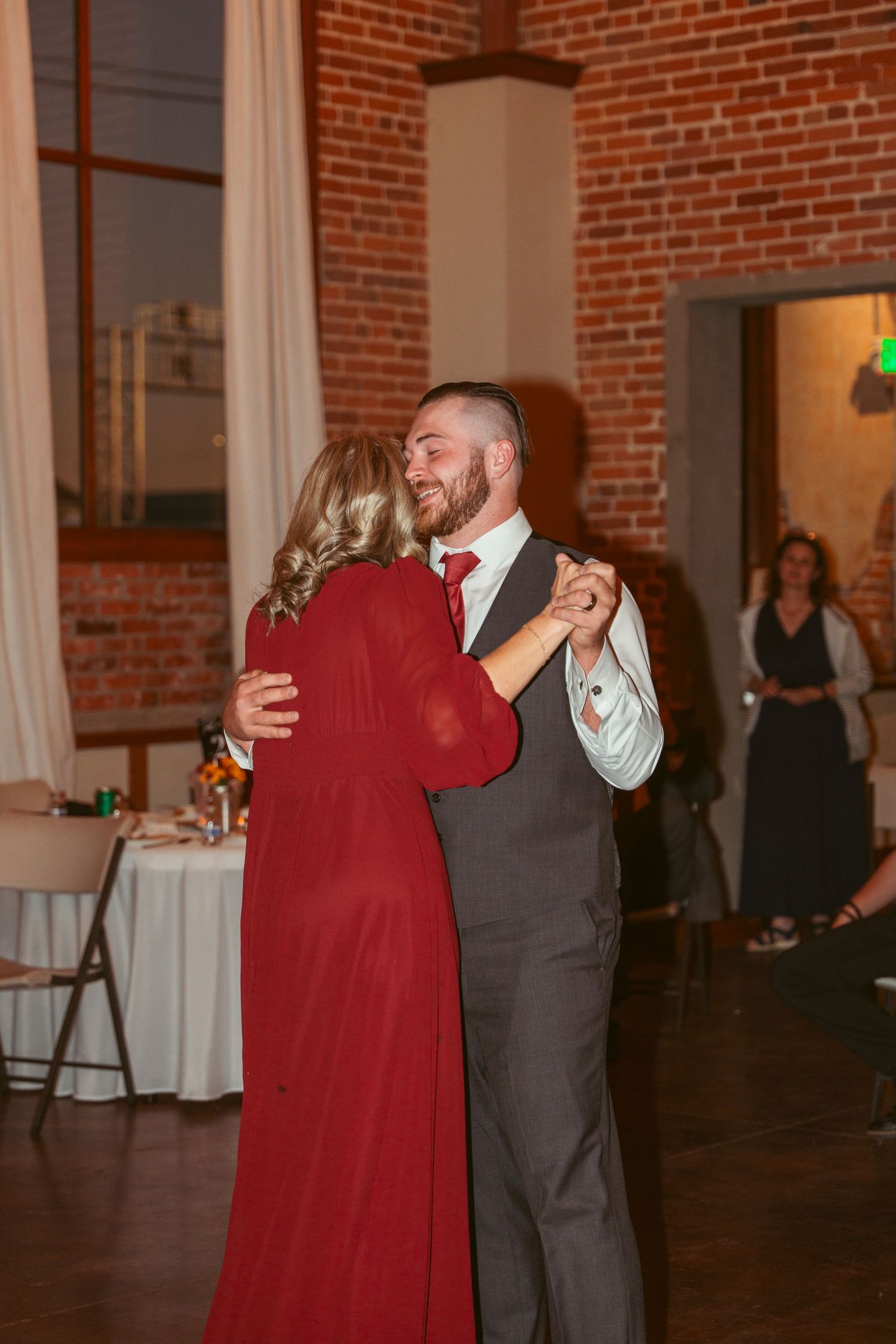 Romantic dance moment captured in historic brick venue with string lights overhead.