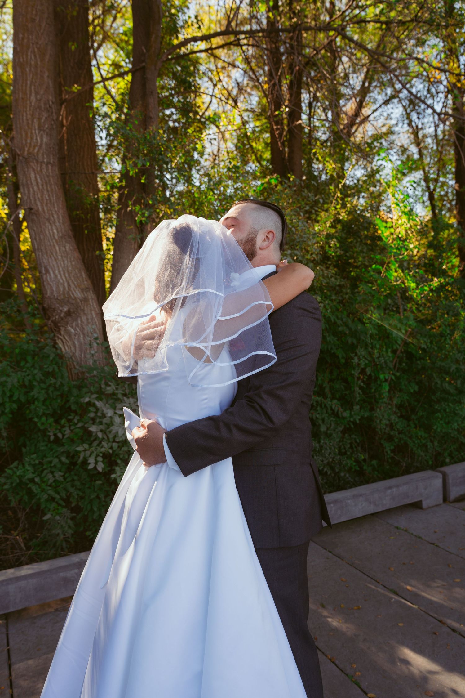A couple embraces on their wedding day surrounded by autumn trees.