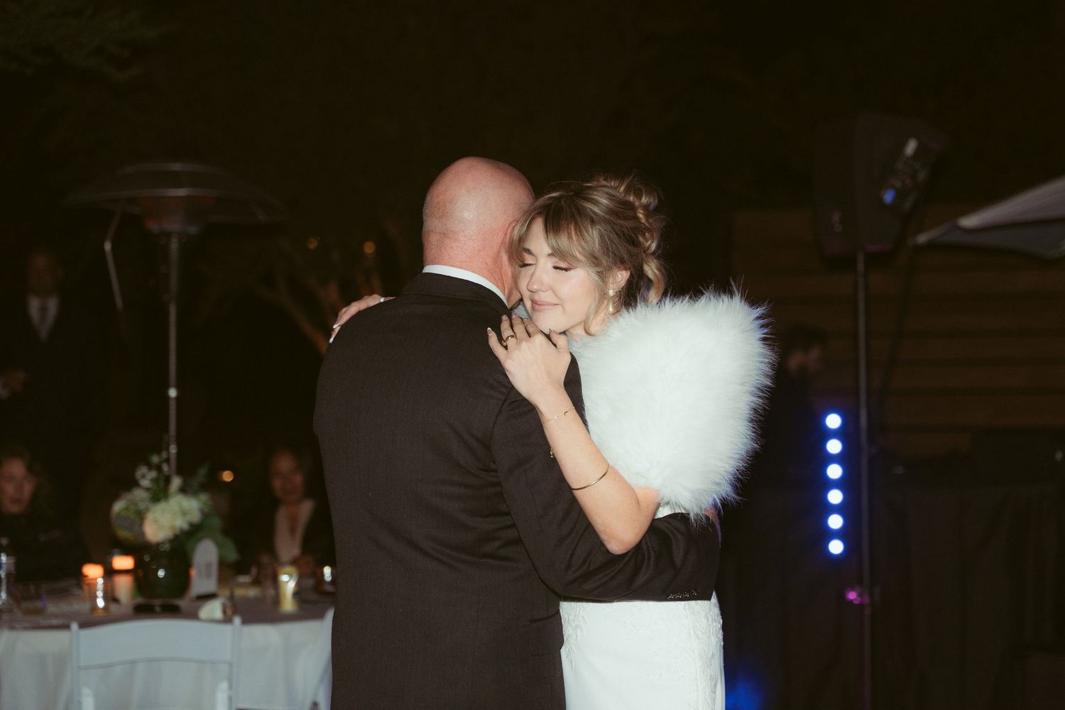 A couple shares their first dance at a wedding reception under dramatic blue lighting.