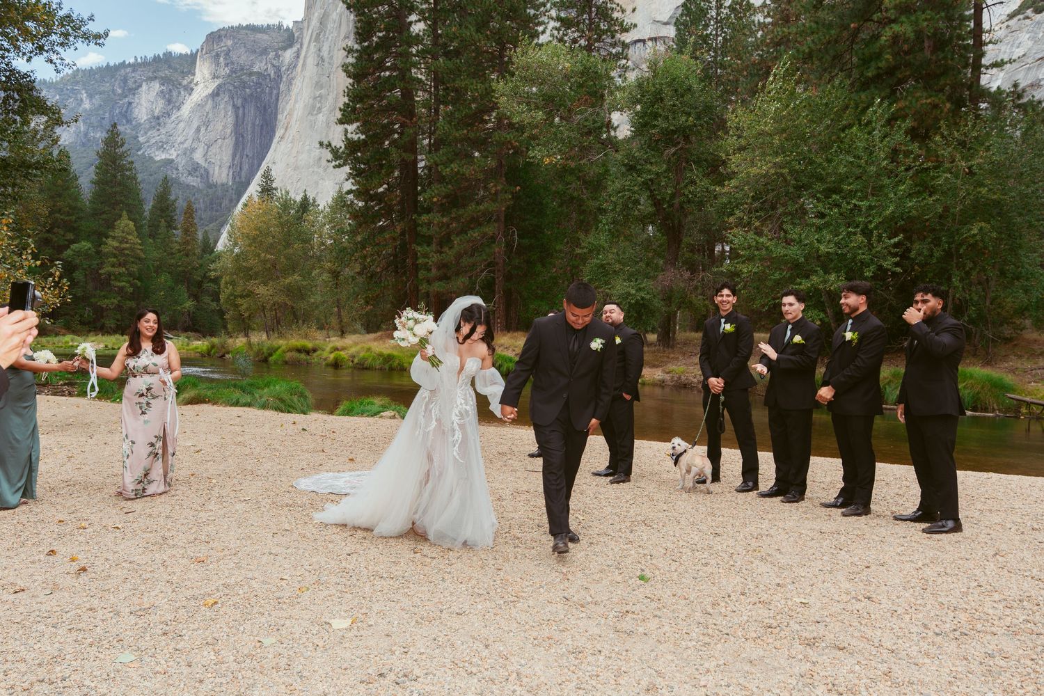 Wedding party gathers on scenic overlook with Yosemite's iconic cliffs in background.