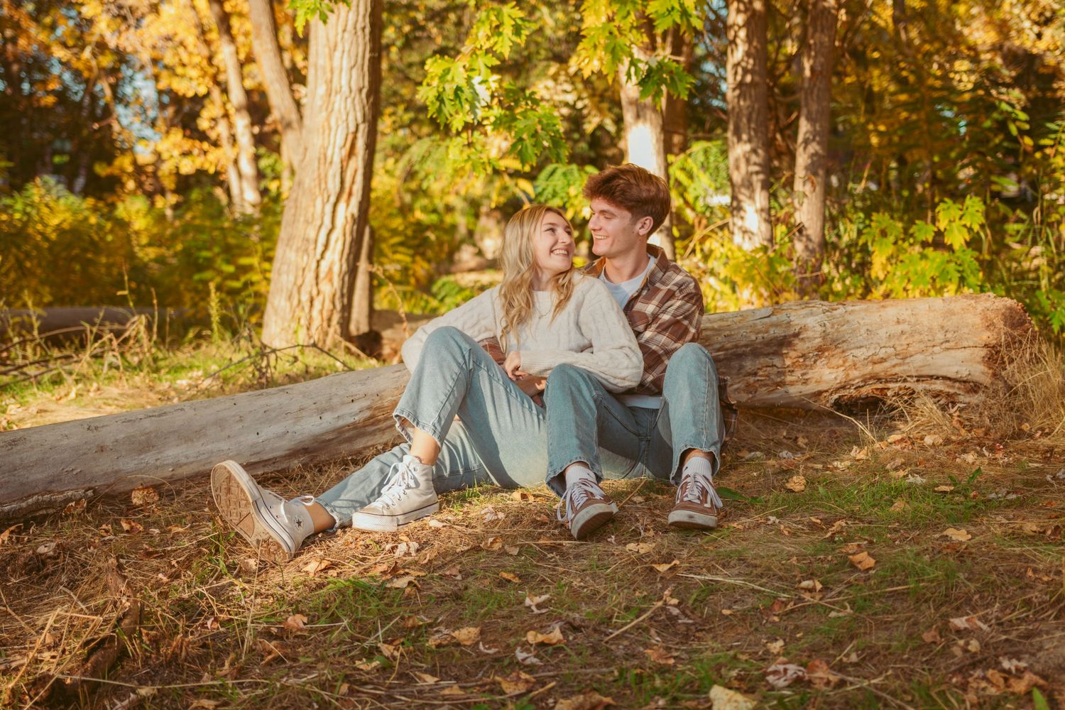 Autumn engagement session with couple relaxing in wooded setting.