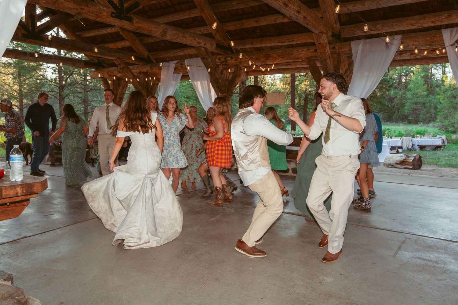 Couples dancing on a wooden dance floor at an outdoor wedding reception.