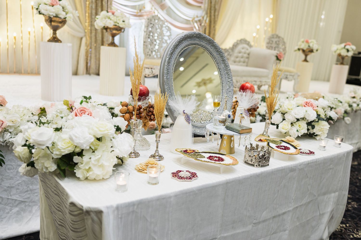 Long banquet table decorated with white floral centerpieces and elegant place settings in a luxurious reception hall.