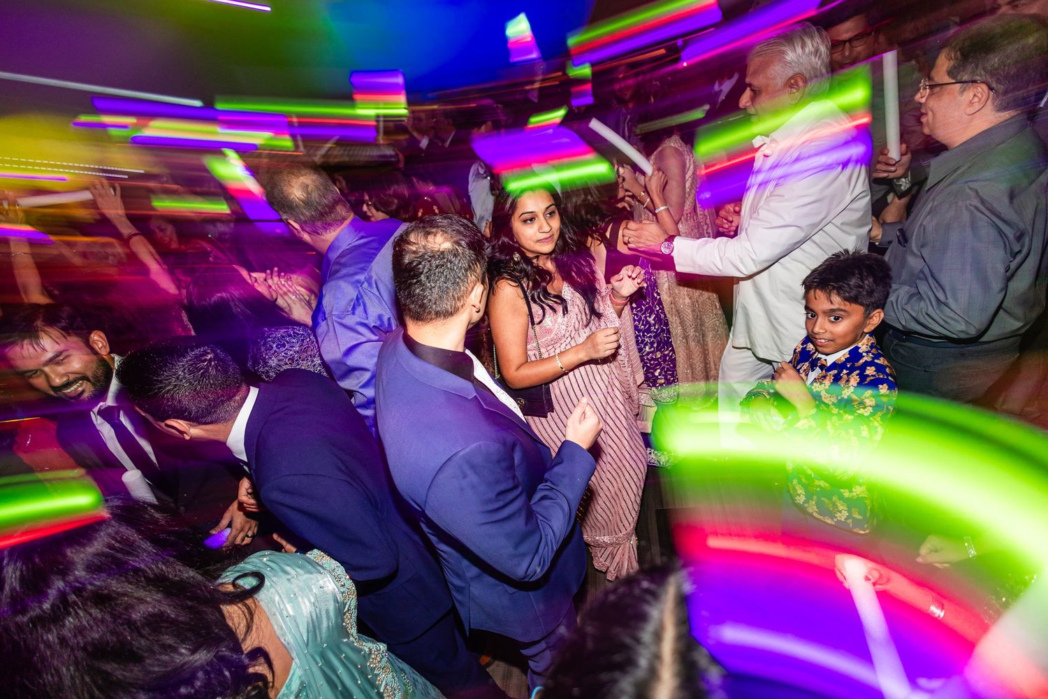 People dancing and enjoying themselves under colorful neon lights at a nightclub party.