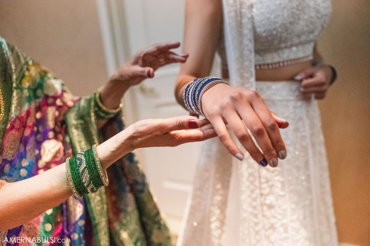 Close-up of hands during a traditional wedding ceremony showing detailed jewelry and attire.