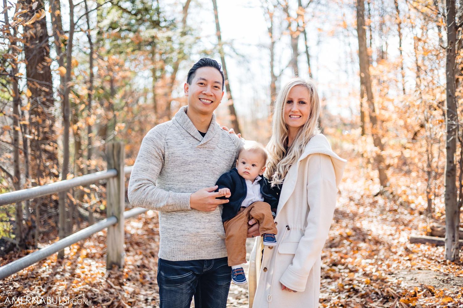 Family poses together on forest trail surrounded by fall foliage.