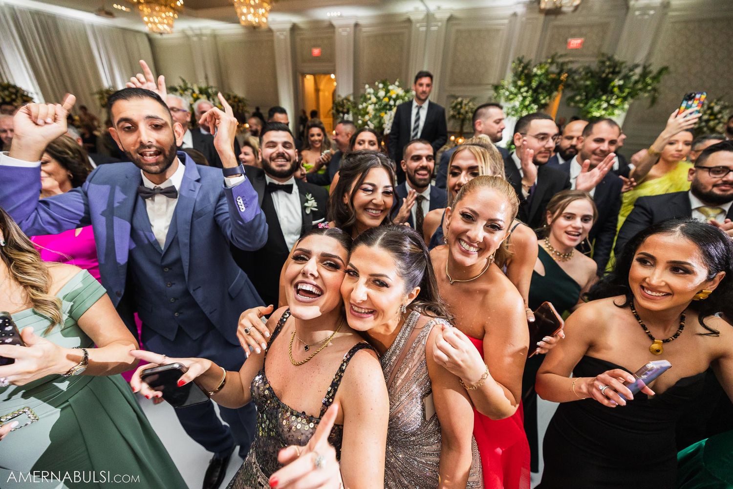 Wedding guests enjoying themselves on a crowded dance floor during reception celebrations.