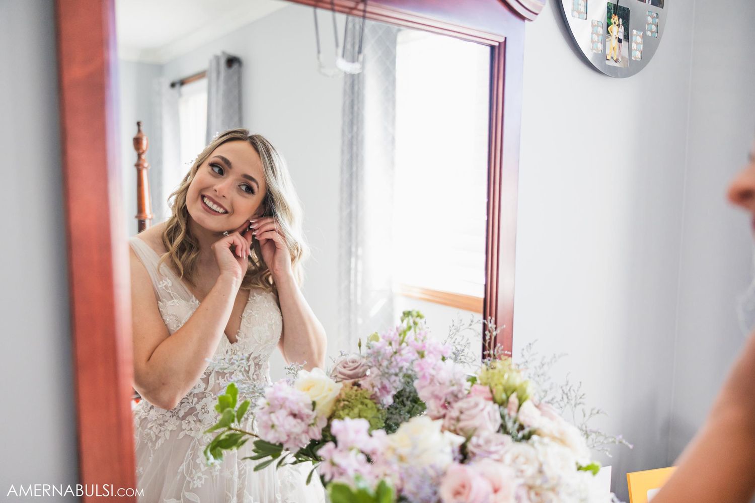 Reflection in mirror shows bridal preparation with flowers in foreground.
