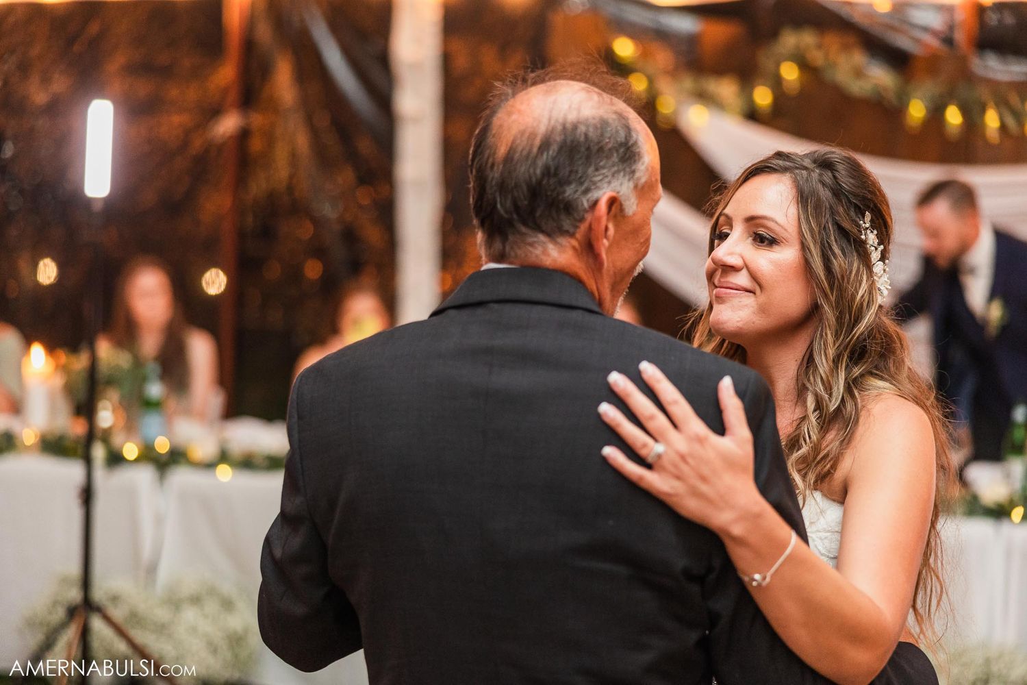 Emotional father-daughter dance captured during outdoor wedding reception.
