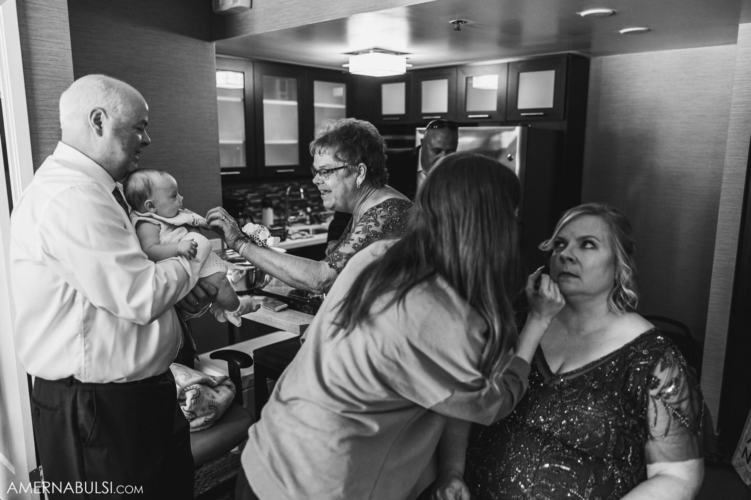 Wedding party getting ready in dimly lit room with makeup artists and stylists.