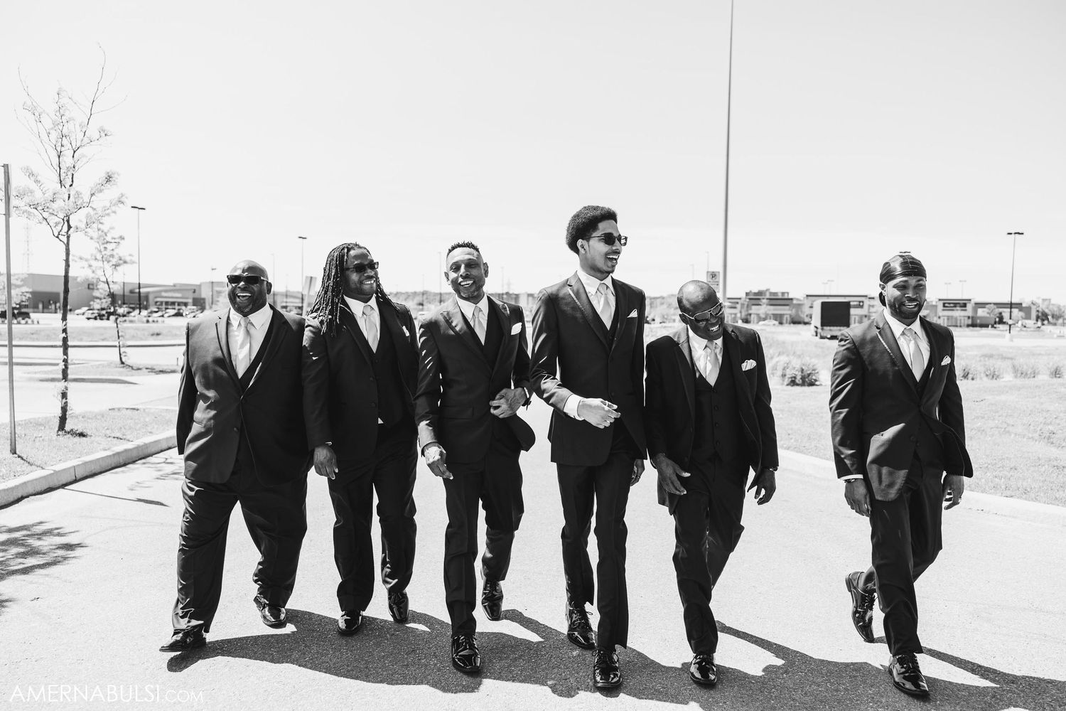 Wedding party in black suits walking together outdoors in black and white photography.