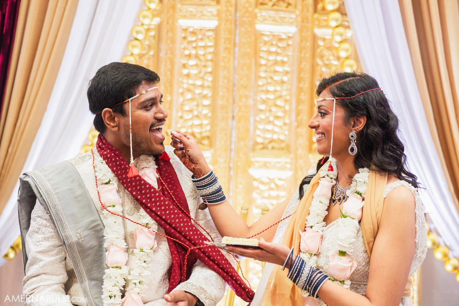 A couple shares a playful moment during their traditional Indian wedding ceremony.