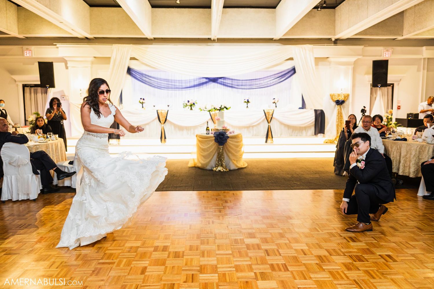 A joyful dance moment at a wedding reception with a beautiful white dress flowing across a parquet dance floor.