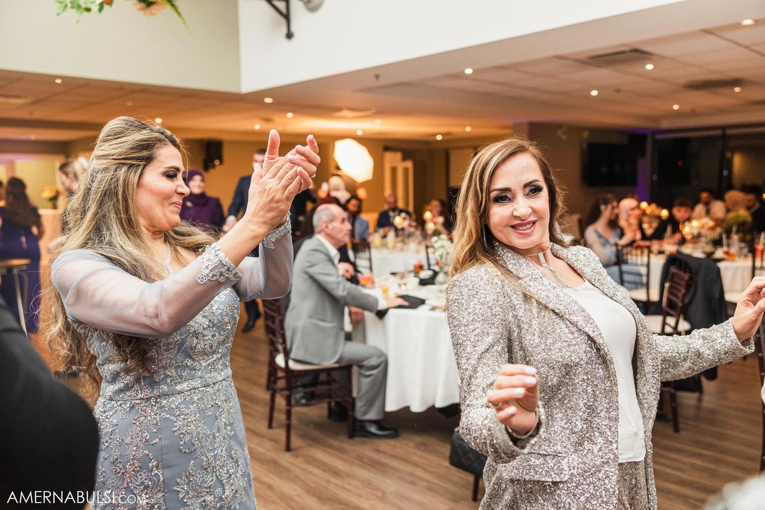Guests in sparkly formal attire dancing together at an indoor reception venue.