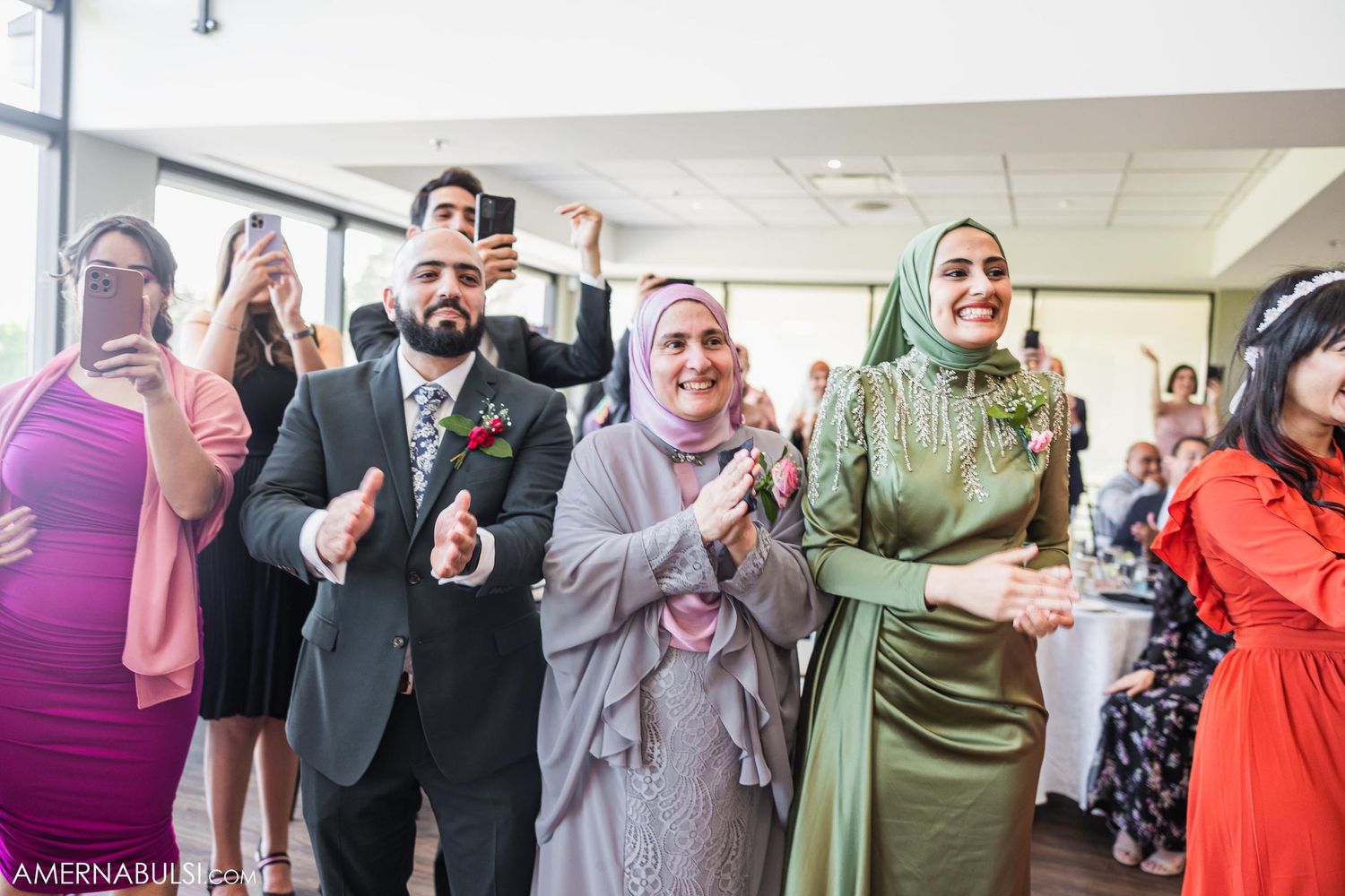 Diverse group of wedding guests applaud during formal reception celebration.