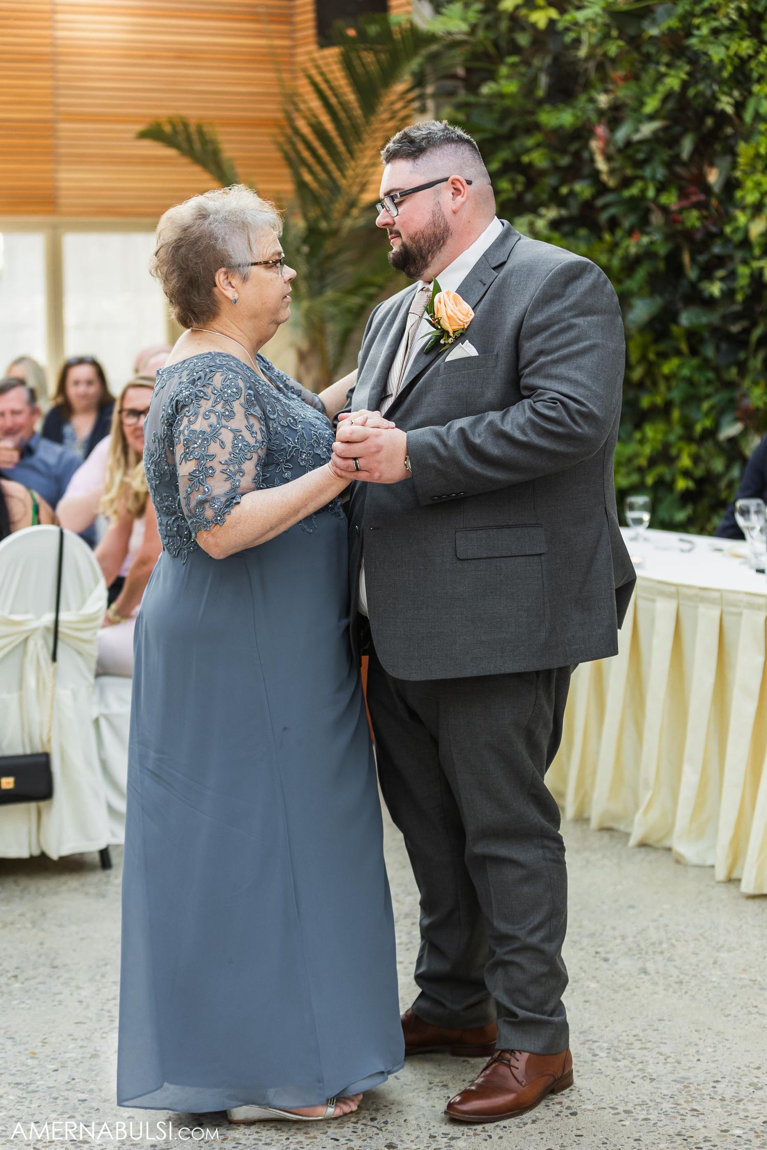 A formal dance between two people in elegant attire at an outdoor wedding reception.