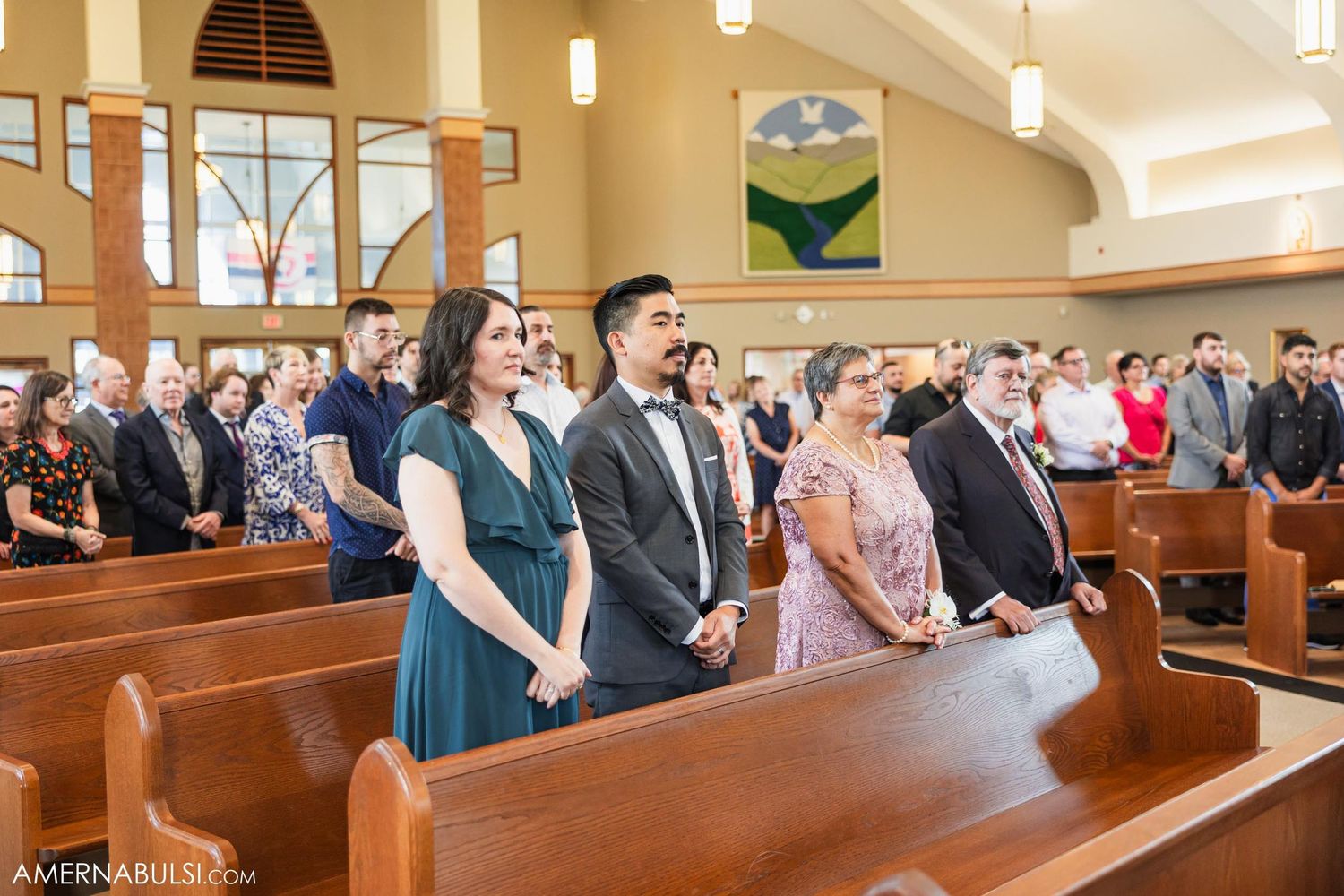 Wedding guests stand in church pews during a traditional ceremony service.